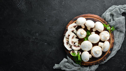 Obraz na płótnie Canvas Champignons mushrooms on a black wooden table. Top view. Free space for text.