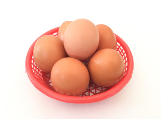 Eggs: brown eggs in a red plastic basket, isolated on a white background in close-up photography from top to bottom, Thailand