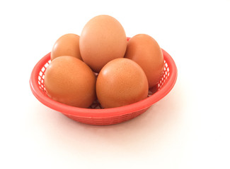 Eggs: brown eggs in a red plastic basket, isolated on a white background in close-up photography from top to bottom, Thailand