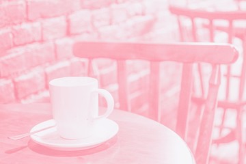 White big cup of coffee latte on the table on the brick wall background. Pink toned