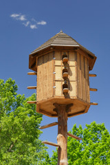 The wooden dovecote on the background of the blue sky