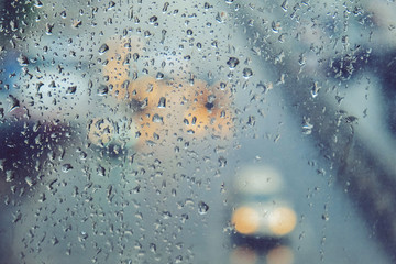 Rain-spattered wet glass through which you can see the road with cars