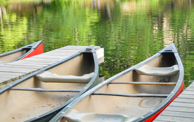 Paddle boats in a lake by the dock. It shows the lake and reflections on the water.