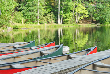 Obraz premium Paddle boats in a lake by the dock. It shows the lake and reflections on the water.