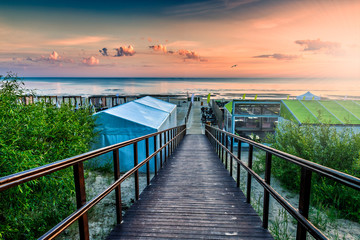 Wooden footpath leading to a sandy beach of The Baltic Sea in Jurmala - famous tourist resort in...