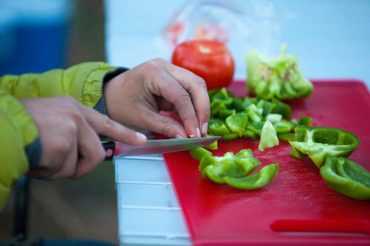 A close up of a woman chopping bell peppers at a campsite at Lava Point, a rock climbing area in Washington State near the foothills of the Cascades.     