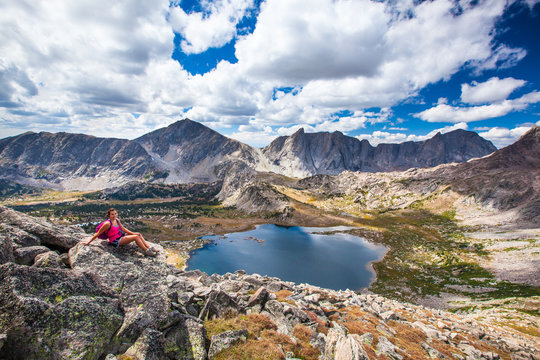 Woman enjoys a rest during a day hike up Pyramid Peak (12,030) in search of better views of the WInd River Range during a backpacking trip in August. Pyramid Lake is pictured below.