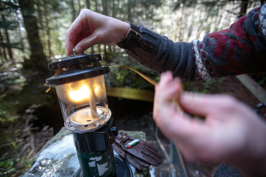 Close up of a man lighting a coleman propane lantern at the entrance to Ape Cave in western Washington State.