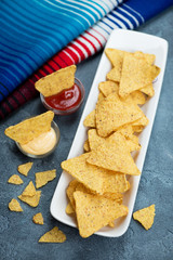 White plate with nachos, vertical shot on a blue stone surface with mexican poncho in the background