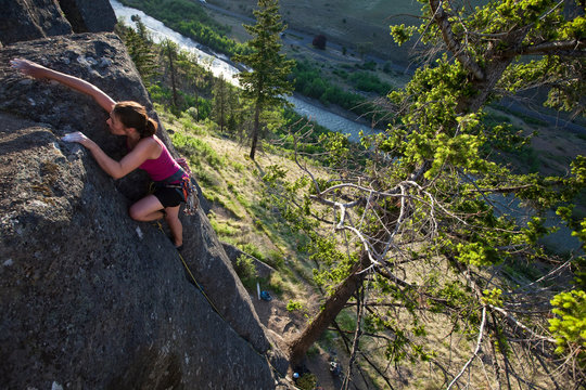 A woman nears the top of a 5.7 crack climb at The Bend, one of more than a dozen crags in Tieton Canyon, a climbing area in Washington State. Tieton River is pictured in the background.