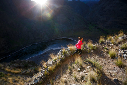 A female trail runner running near Suicide Point along the scenic Snake River National Recreation Trail (#102) in Hells Canyon along the Oregon-Idaho border. The canyon is the deepest river gorge in North America with more than a mile of vertical elevation between the river floor and nearby peaks in the Seven Devil Mountains.