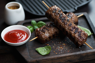 Close-up of barbecued marbled beef skewers on a wooden serving tray, studio shot