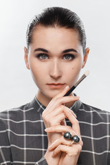 Portrait of a make-up artist in a gray plaid shirt, with a chain in her hands and with picked up...