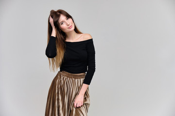 Photo portrait of a beautiful pretty brunette girl in a black sweater on a gray background. A woman is satisfied with her life, she stands in front of the camera, smiling and talking. Made in studio.