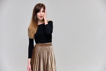 Photo portrait of a beautiful pretty brunette girl in a black sweater on a gray background. A woman is satisfied with her life, she stands in front of the camera, smiling and talking. Made in studio.