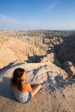 A woman enjoying a dramatic view of the dirt spires near the Sage Creek Road turnoff in Badlands National Park, South Dakota at dusk.