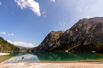 Lake Prags, Prags Dolomites, South Tyrol, Italy: A woman with an analog camera hanging over her shoulder at the shore of Lake Prags.