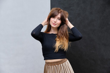 Beauty portrait of a beautiful pretty brunette girl in a black sweater on a two-color background. A woman is happy with life, stands in front of the camera, smiles. Made in a studio.