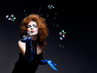 Woman mime with theatrical makeup and soap bubbles.