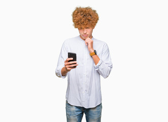 Young handsome man using smartphone serious face thinking about question, very confused idea