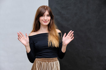 Beauty portrait of a beautiful pretty brunette girl in a black sweater on a two-color background. A woman is happy with life, stands in front of the camera, smiles. Made in a studio.