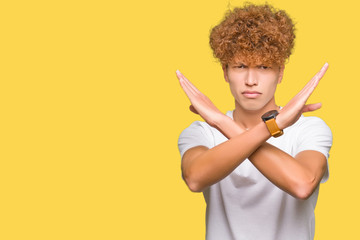 Young handsome man with afro hair wearing casual white t-shirt Rejection expression crossing arms doing negative sign, angry face