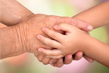 Hands of young child and old senior on background