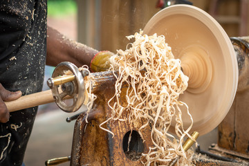 An African American older man creates works of art through bowl turning on a lathe. This shows him...