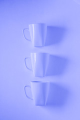 3 blue coffee mugs on blue background in a vertical row with empty copyspace