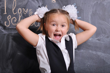 Portrait of beautiful smiling young first-grader on blackboard background. school and education...
