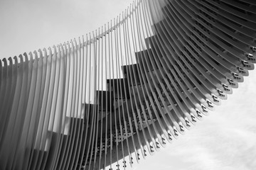 Details of curved metal stairs  against a sky background. Black and white photography.