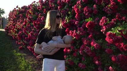 Gimbal shot. Young mother with newborn son walking among fence. 4K