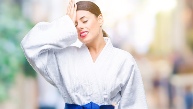 Young beautiful woman wearing karate kimono uniform over isolated background surprised with hand on head for mistake, remember error. Forgot, bad memory concept.
