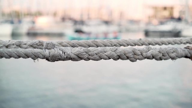 Seaport. Ship ropes. The quay with yachts. White yachts are anchored in the city port on a Sunny day. The port in the city. Flags on yachts in the wind. Boats on the background