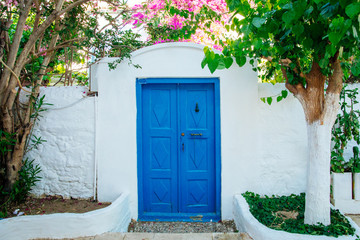 Fototapeta na wymiar Traditional Aegean style white houses, colorful streets and bougainvillea flowers in Bodrum city of Turkey. White colored architecture in Bodrum town Turkey.