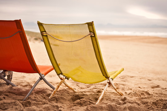 Fototapeta Two beach chairs with spanish coast in the background in Plage des Casernes, France