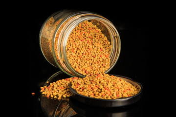 closeup raw bee pollen grain poured out from glass jar