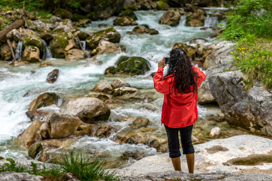 Woman taking a picture of a turquoise river with her smartphone