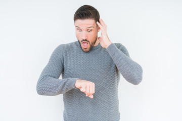 Young handsome man wearing casual sweater over isolated background Looking at the watch time...