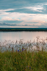 Dramatic beautiful pink blue orange sunset at river with reflection and clouds on natural background
