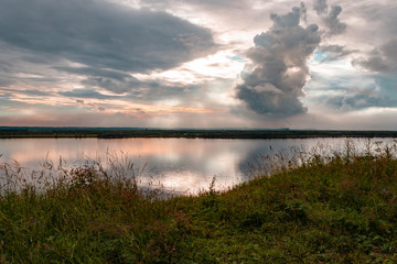 Dramatic beautiful pink blue orange sunset at river with reflection and clouds on natural background