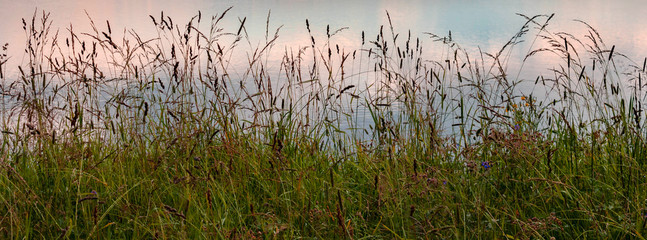 Dramatic beautiful pink blue orange sunset banner with sky and clouds reflection in river by medow