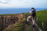 Photographer exploring the Cliffs of Moher at sunset
