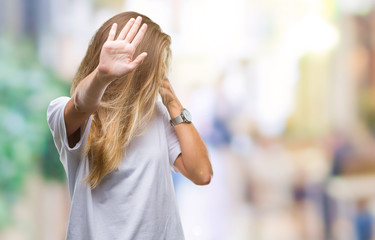 Young beautiful blonde woman wearing casual white t-shirt over isolated background covering eyes with hands and doing stop gesture with sad and fear expression. Embarrassed and negative concept.