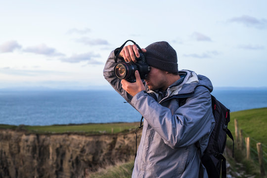 Photographer exploring the Cliffs of Moher at sunset