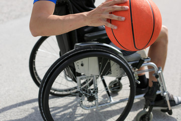 Disabled young basketball player on a wheelchair holding ball and beeing active in sport