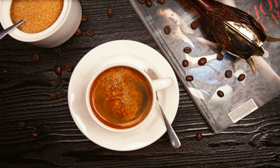 Foam milky cappuchino in white cup decorated with coffee beans and journals.
