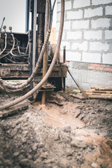 The well drilling machine works near the construction of a new house of gas silicate blocks