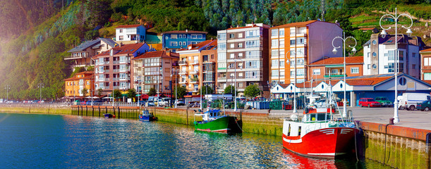 Pueblo de Ribadesella en Asturias, España.Barcos pesqueros en el puerto y paseo maritimo - obrazy, fototapety, plakaty