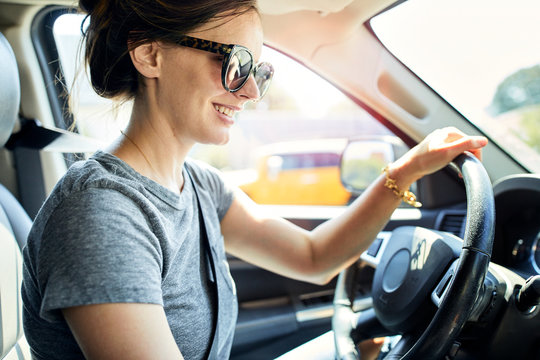 Smiling woman wearing sunglasses while driving car